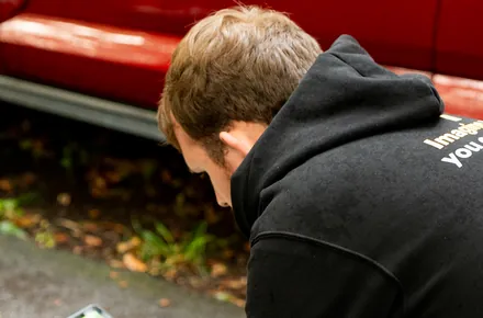 Kian setting up a low shot beside a red car