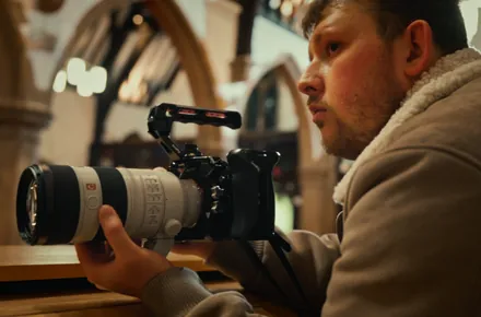 Kian with a camera and telephoto lens in a church hall