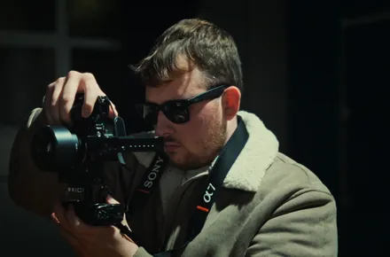 Kian shooting handheld on a dark set