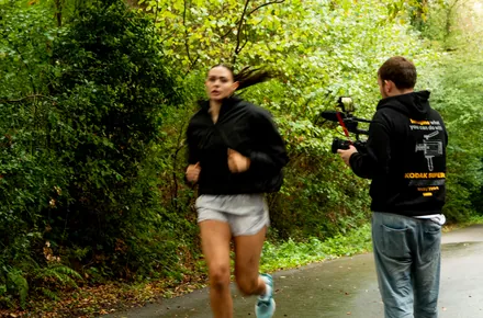 Kian following a runner down a wooded lane with a gimbal