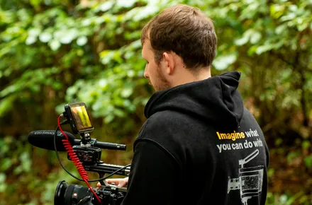 Kian holding the camera rig in a wooded lane