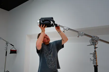 Kian lifting a light onto a boom stand in a white studio
