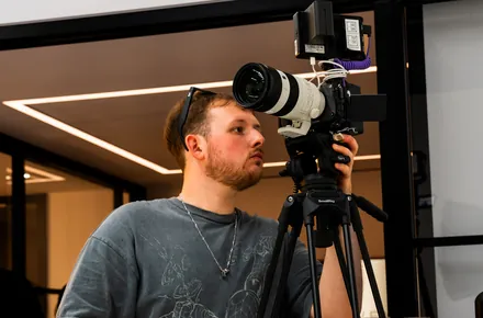 Kian operating a camera on a tripod in the studio